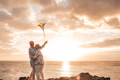 Man standing at beach against sky during sunset