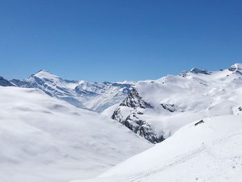 Scenic view of snowcapped mountains against clear blue sky