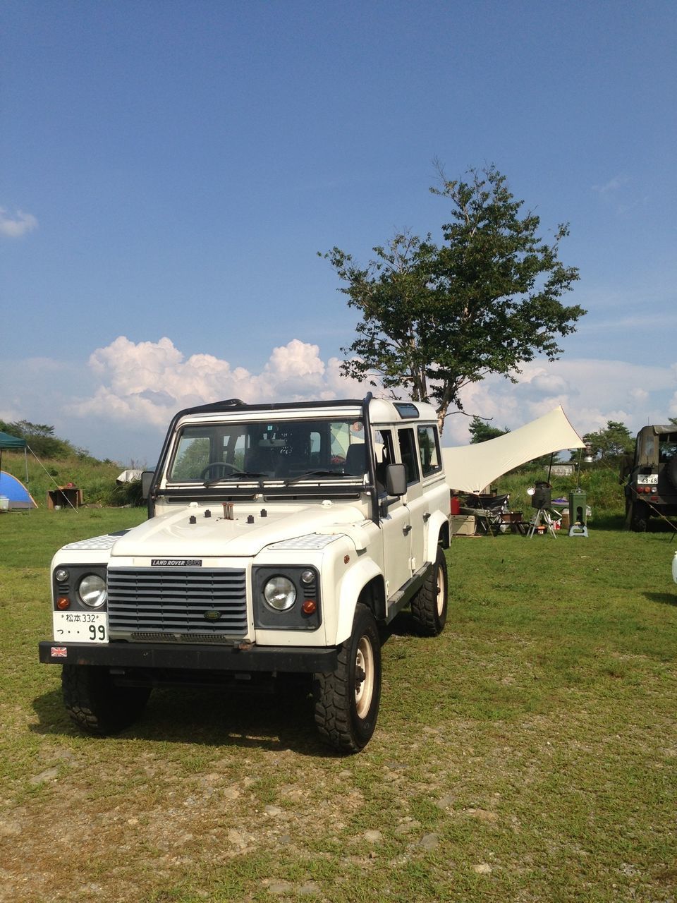 transportation, grass, land vehicle, mode of transport, car, field, sky, grassy, tree, landscape, day, stationary, green color, nature, blue, vehicle, outdoors, sunlight, travel, parking