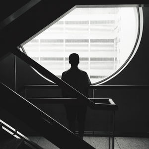 Rear view of man looking through window