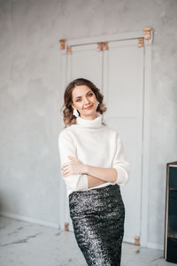 Portrait of young woman standing against wall