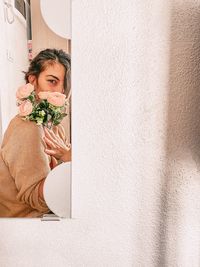 Portrait of a young woman holding food against wall