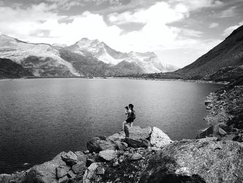 Woman photographing lake against mountains