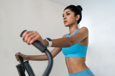 Young woman training at the gym using eliptical crosstrainer