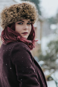 Close-up portrait of young woman in warm clothing standing outdoors