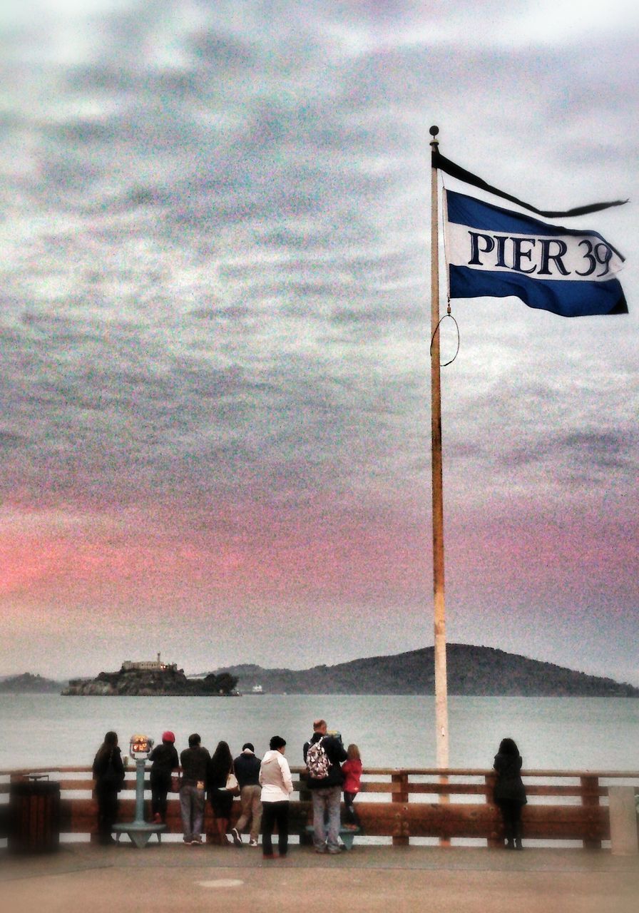 sky, cloud - sky, sea, water, men, beach, lifestyles, sunset, person, leisure activity, cloudy, horizon over water, standing, cloud, flag, silhouette, nature, shore, text