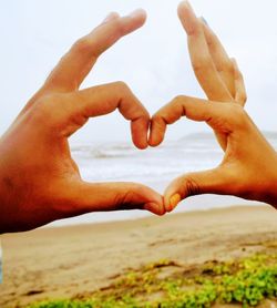 Close-up of couple hands against sky