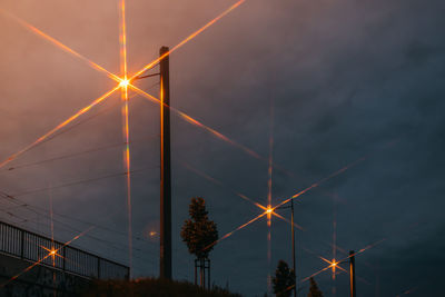 Low angle view of illuminated lights against sky at sunset