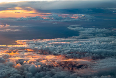 Photo taken from an airplane of the beautiful orange and red colored clouds 
