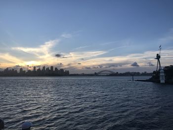 View of city at waterfront against cloudy sky