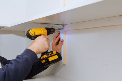 Cropped hand of man working with nail gun at home