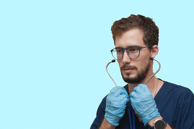 Portrait of young man wearing eyeglasses against blue sky