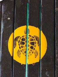 Close-up of yellow sign hanging on wall