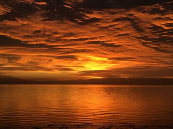 Scenic view of sea against dramatic sky during sunset