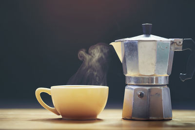 Close-up of coffee cup on table against black background