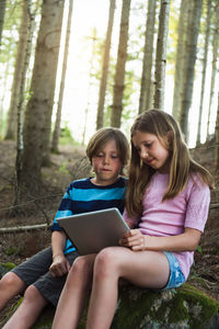 Boy and girl using digital tablet in forest