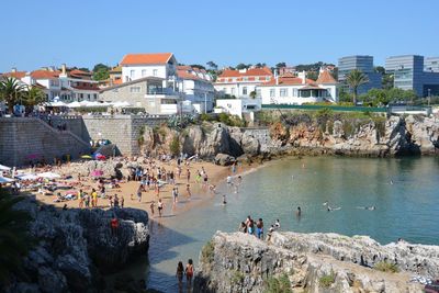 People on beach by city against sky