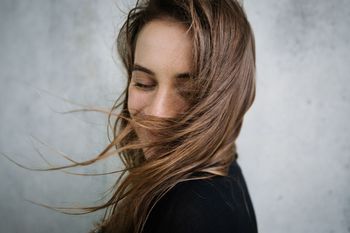 PORTRAIT OF WOMAN AGAINST WALL