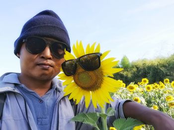 Portrait of man wearing sunglasses by sunflower