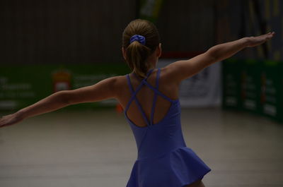 Rear view of girl with arms outstretched dancing on floor