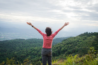 Rear view of woman standing by tree against mountain