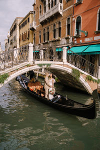 Couple standing in gondola at canal