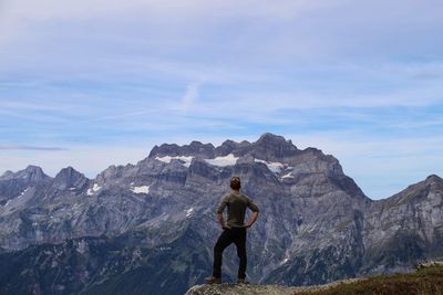 Rear view of man standing on rock against sky