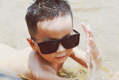 Portrait of shirtless boy with sunglasses at beach