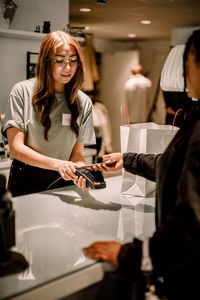 Female customer paying through smart phone to saleswoman at store