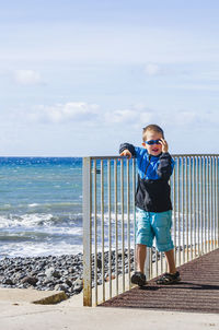 Boy with sunglasses walking besides sea