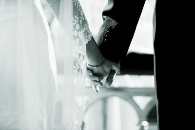 Midsection of bride and bridegroom holding hands