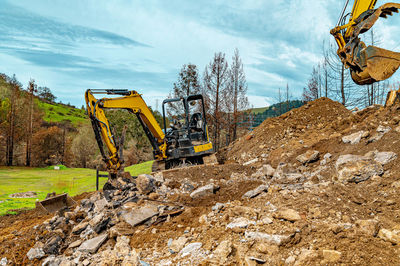 Excavators in quarry. extraction of natural building materials. background blue sky, mountains