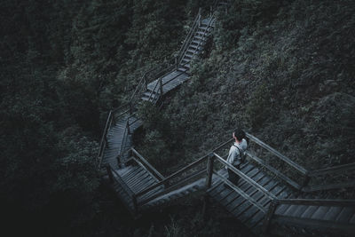 High angle view of young man standing on steps at forest