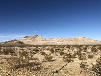 Scenic view of arid landscape against clear blue sky