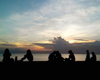 Silhouette of people on beach at sunset