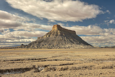 Scenic view of desert against cloudy sky