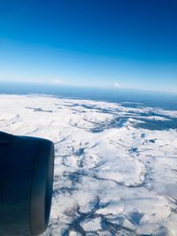 Airplane flying over snowcapped mountains against blue sky