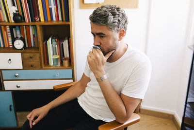 Contemplative depressed man sitting on chair in therapy office