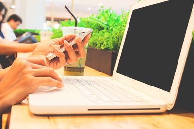 Midsection of person holding smart phone on table