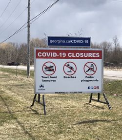 Information sign on field against sky