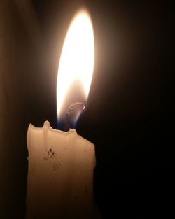 Close-up of lit candle in darkroom