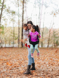 Mother and kids playing in park during autumn