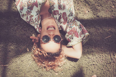 High angle portrait of smiling young woman lying on field