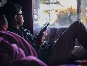 Side view of man using mobile phone at home