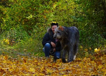 Woman with dog crouching on grassy field