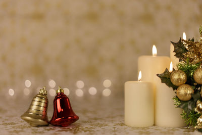 Close-up of christmas bells with illuminated candles on table