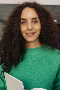 Portrait of smiling female entrepreneur with curly hair at office