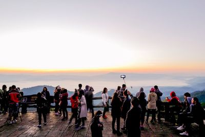 People at observation point against sky during sunset