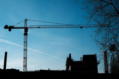 Low angle view of silhouette crane against sky at dusk