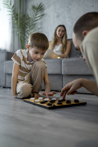 Father playing checkers with son at home